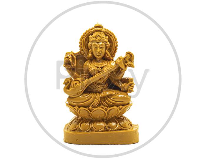 The Statue Of Saraswati Carved In Brown Wood Is Isolated In White