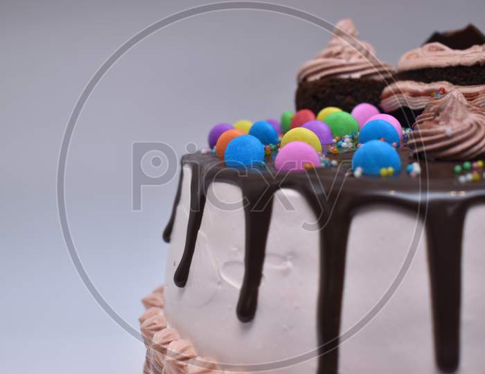 Tasty Chocolate And Creamy Cake Garnished With Gems On Top Of It