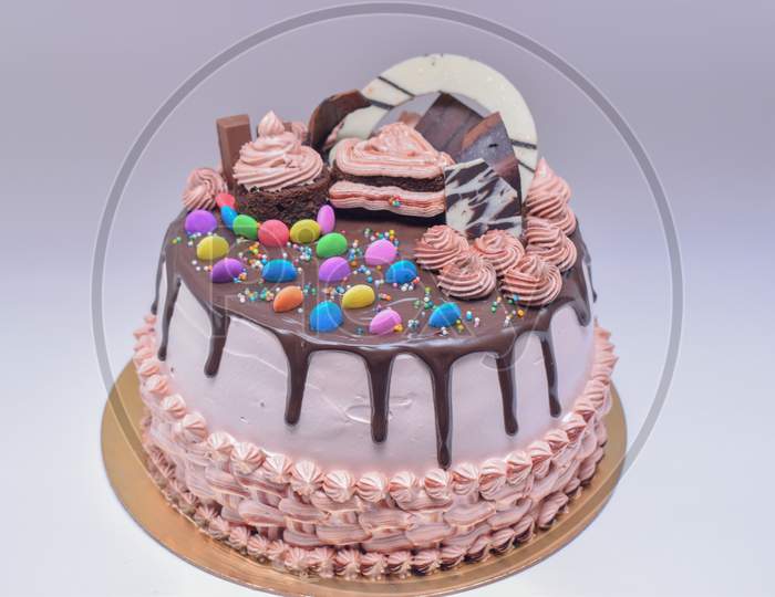 Tasty And Beautiful Chocolate Cake Garnished With Gems And Chocolate Sauce .Cake With White Background