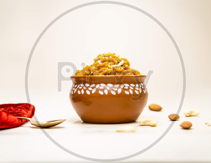Front View Of Indian Sweet Moong Dal Halwa In Matka With Scattered Dry Fruits