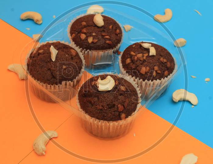 Chocolate Muffin Isolated On Color Background. Delicious Chocolate Muffin With Nuts.