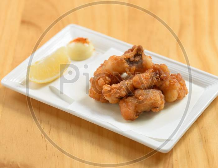 Japanese Food Fried Tako Karaage With Lemon In A White Dish Isolated On Wooden Table Top View