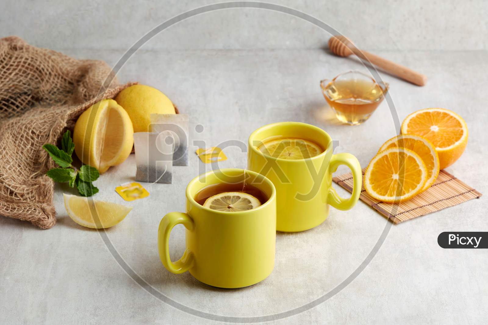 Two Yellow Cup Of Warming Honey Citron Tea With Slices Of Orange And Lemon.