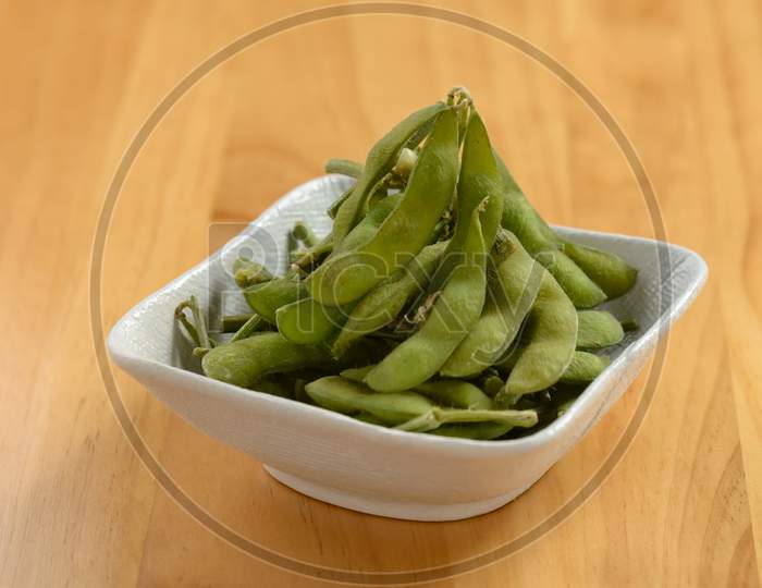 Fresh Steamed Edamame In A White Bowl On Wooden Background Top View