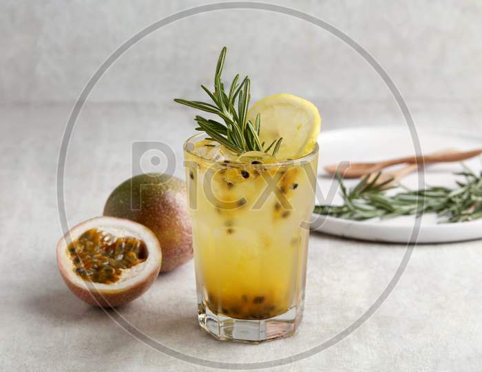 A Glass Of Iced Passion Fruit Soda With Lemon And Passion Fruit Half Slice On Grey Background, A Healthy Summer Drink