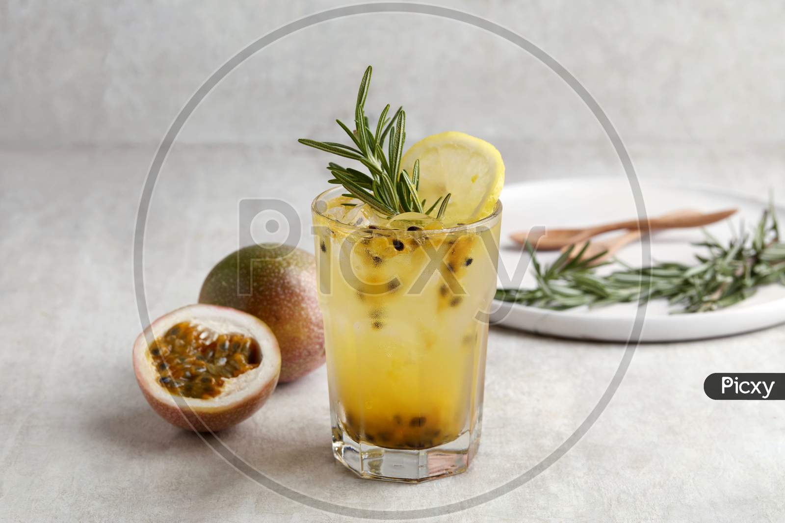 A Glass Of Iced Passion Fruit Soda With Lemon And Passion Fruit Half Slice On Grey Background, A Healthy Summer Drink