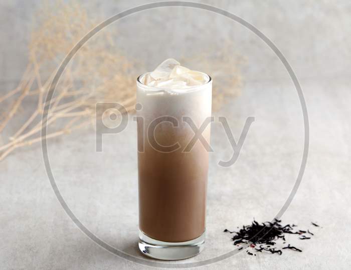 Glass Of Iced Milk Tea With Ice Cubes On Grey Background