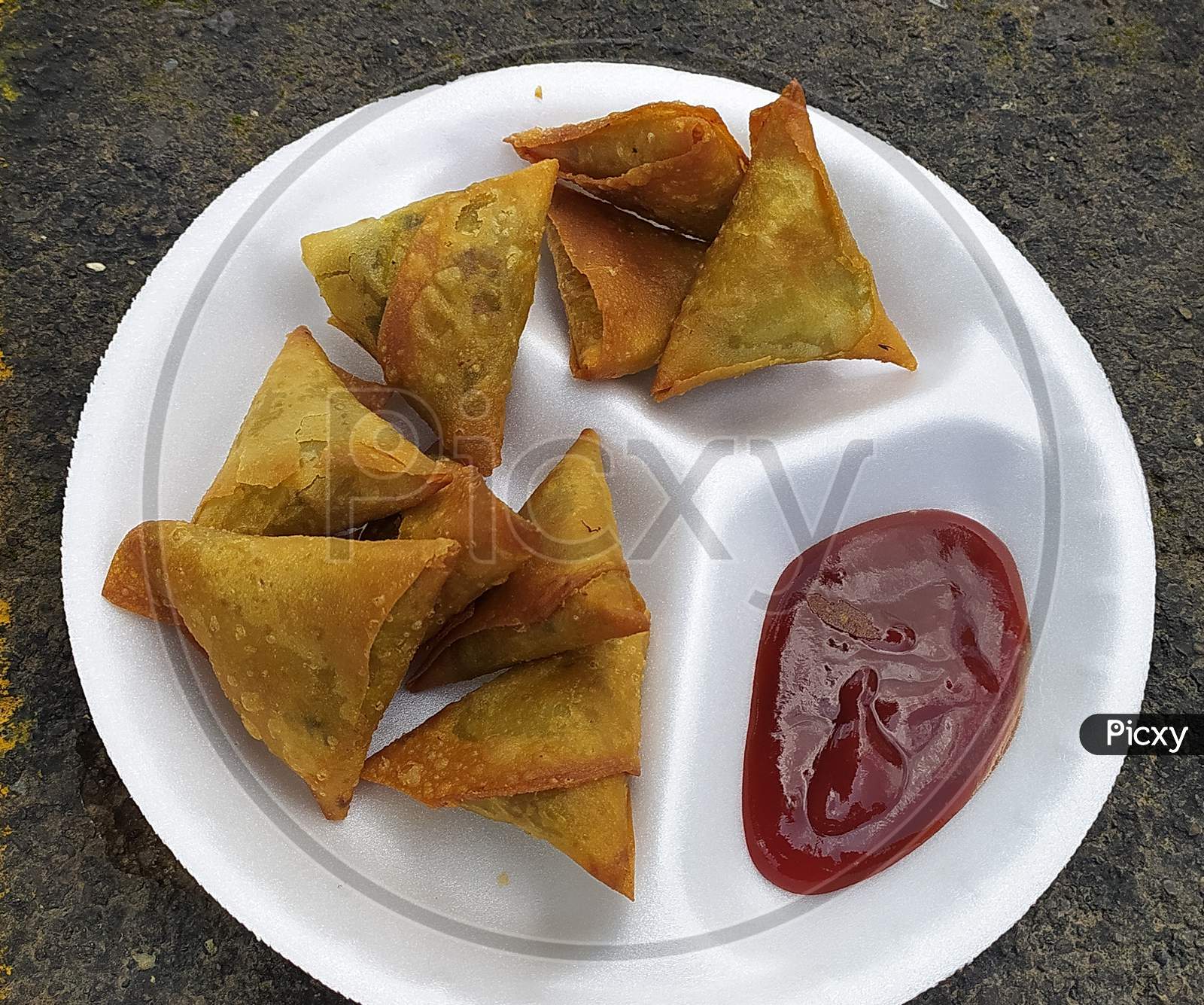 Fried samosa in disposable dish with tomato ketchup